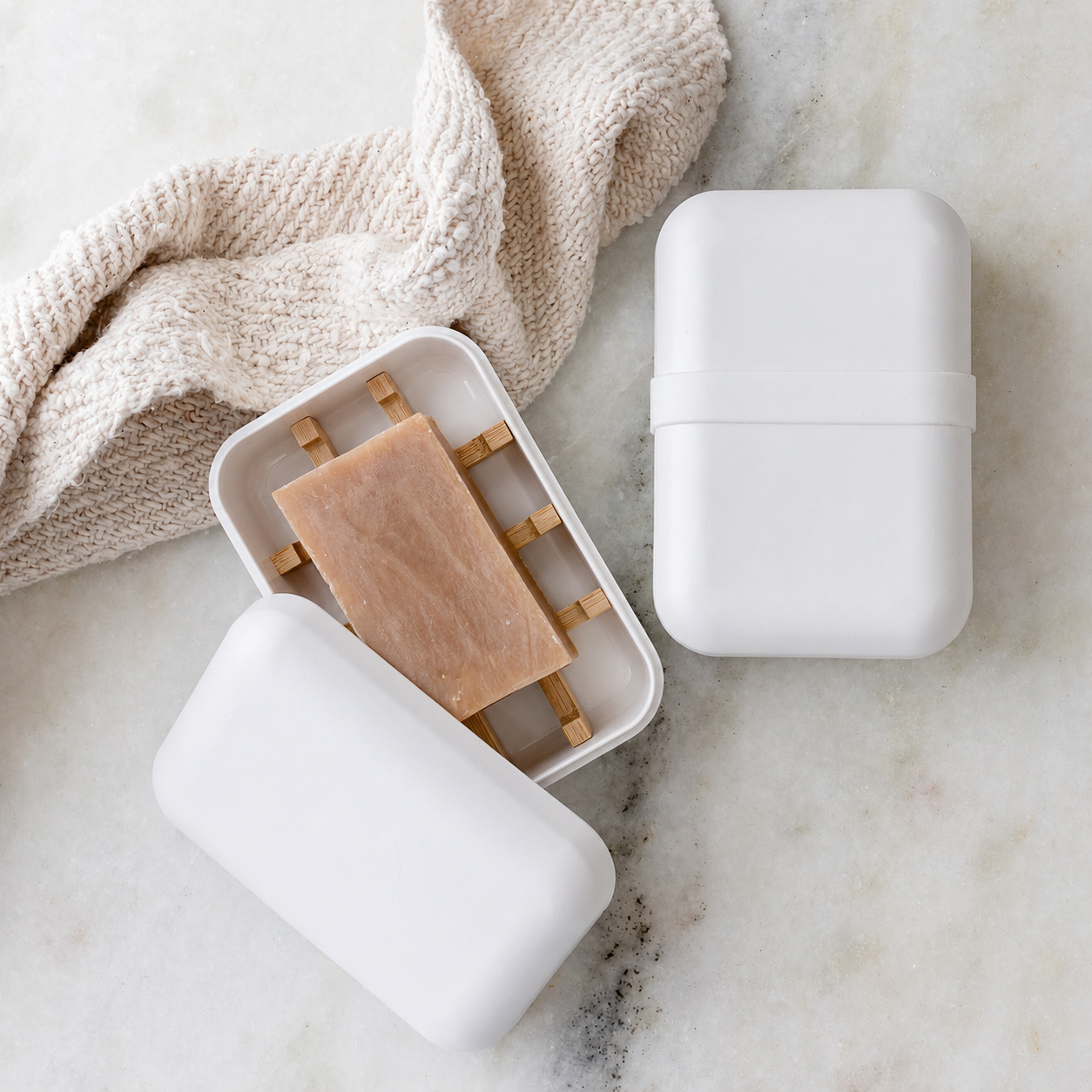 White bamboo-fiber travel soap case open, showing the removable bamboo draining grid inside
