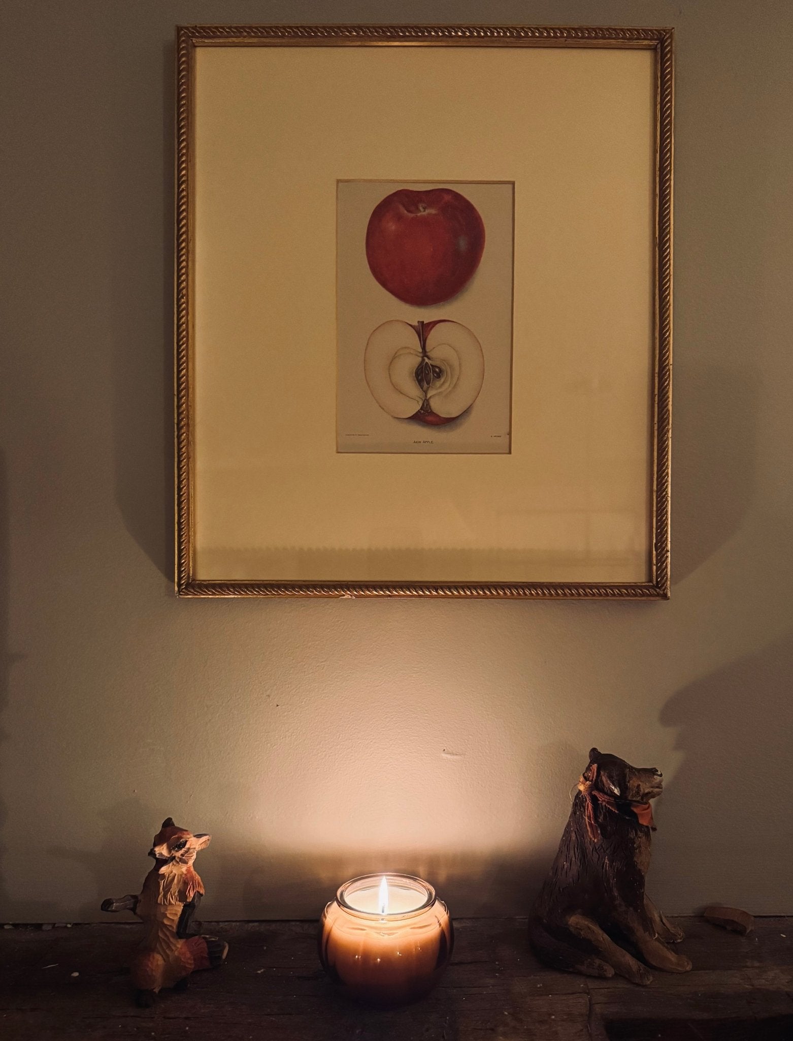 Caramelled Apple candle in a rustic cottage with apple artwork hanging above