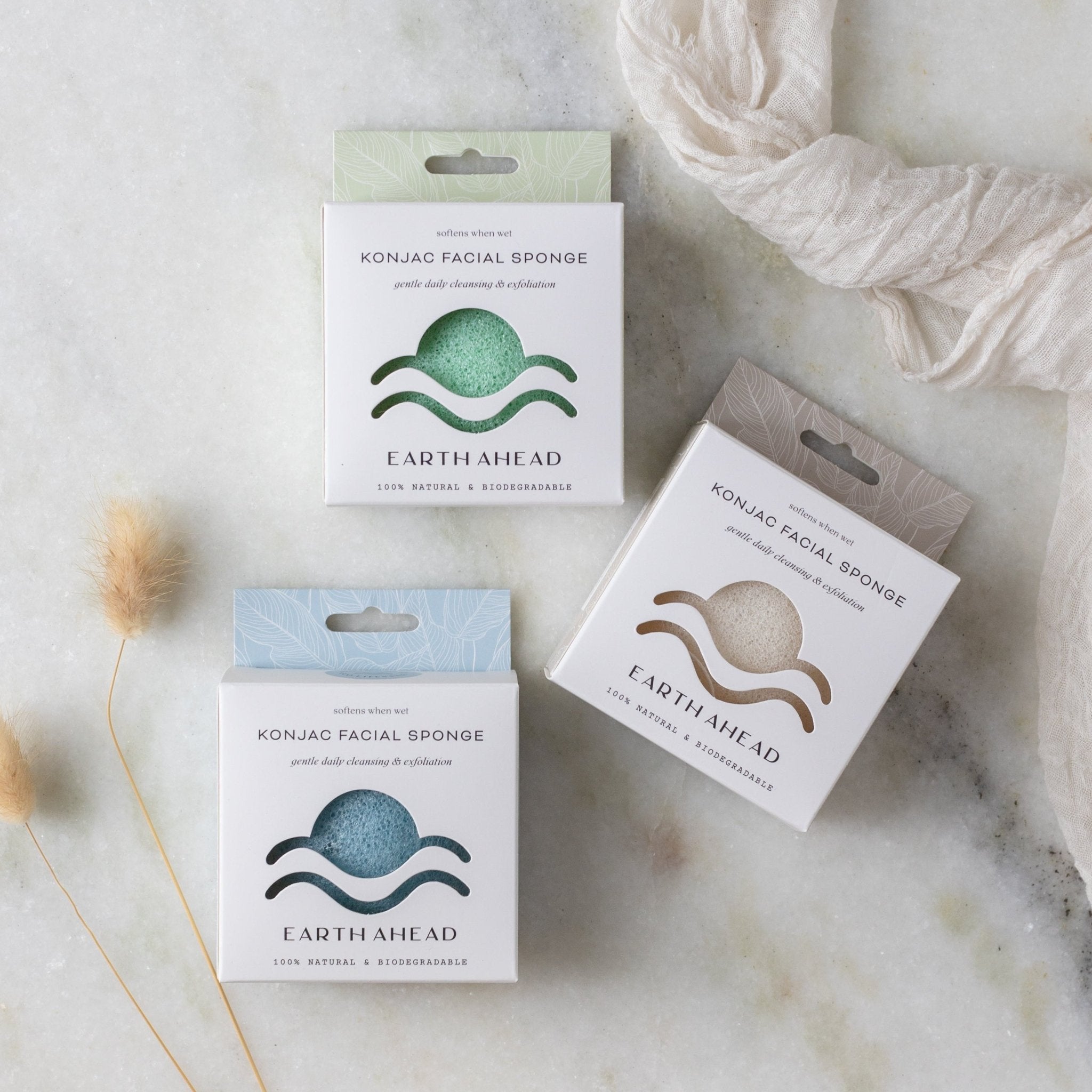 Three boxed konjac facial sponges in green, blue, and natural white