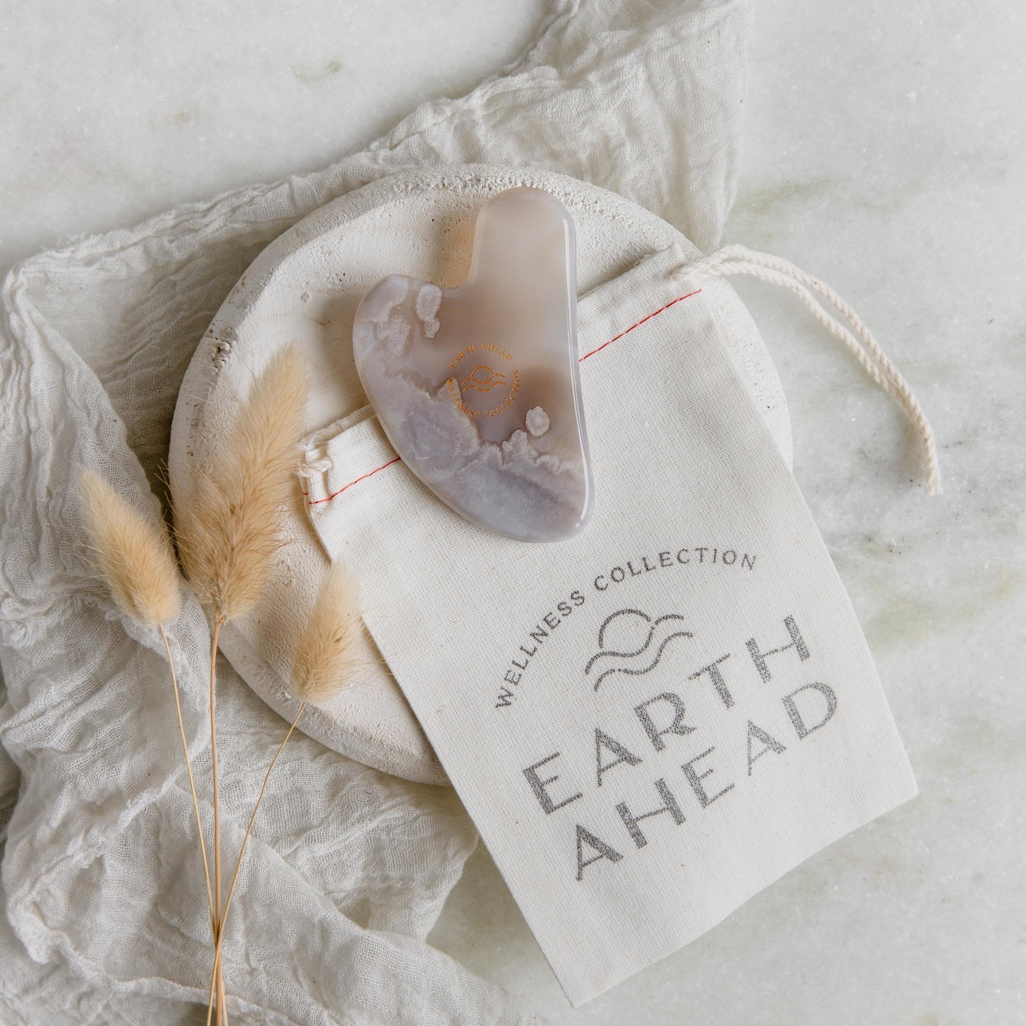 Natural crystal Gaia Grey Agate Gua Sha Facial Massage Tool on top of Wellness Collection cotton pouch - Earth Ahead