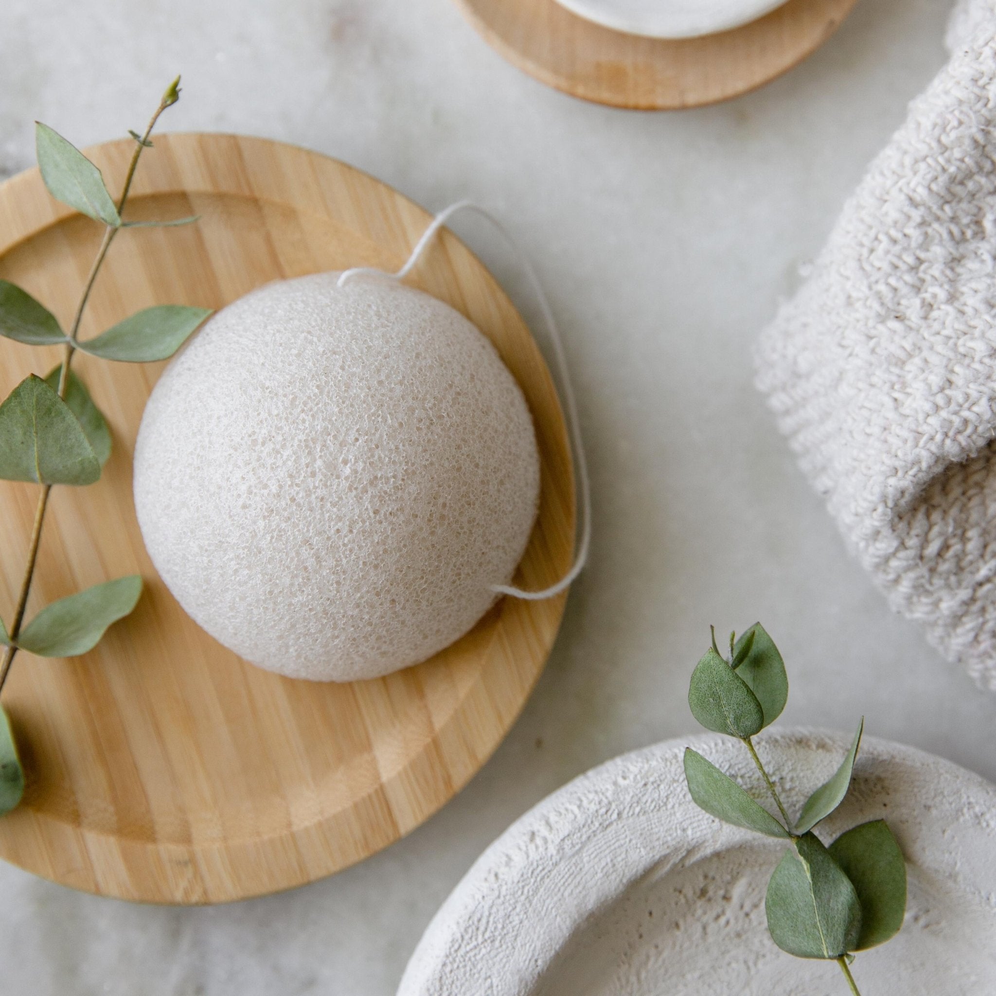 Natural white konjac facial sponge on a bamboo dish with eucalyptus