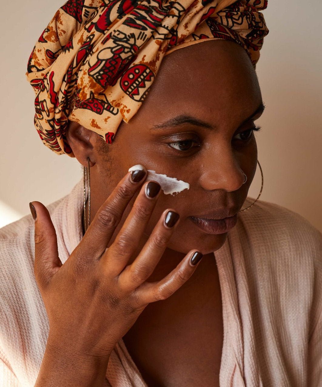 A black woman applying natural, plastic-free UpCircle Face Moisturizer with Argan Powder on her face